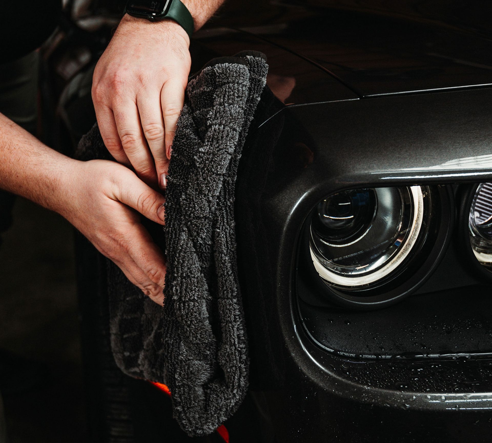 A person is cleaning a car with a towel.