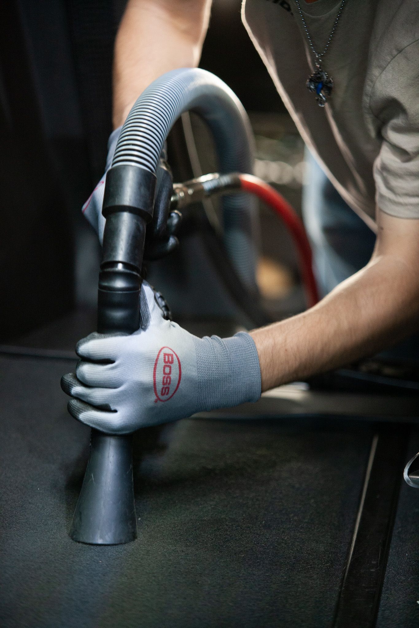 A person wearing gloves is using a vacuum cleaner to clean a carpet.