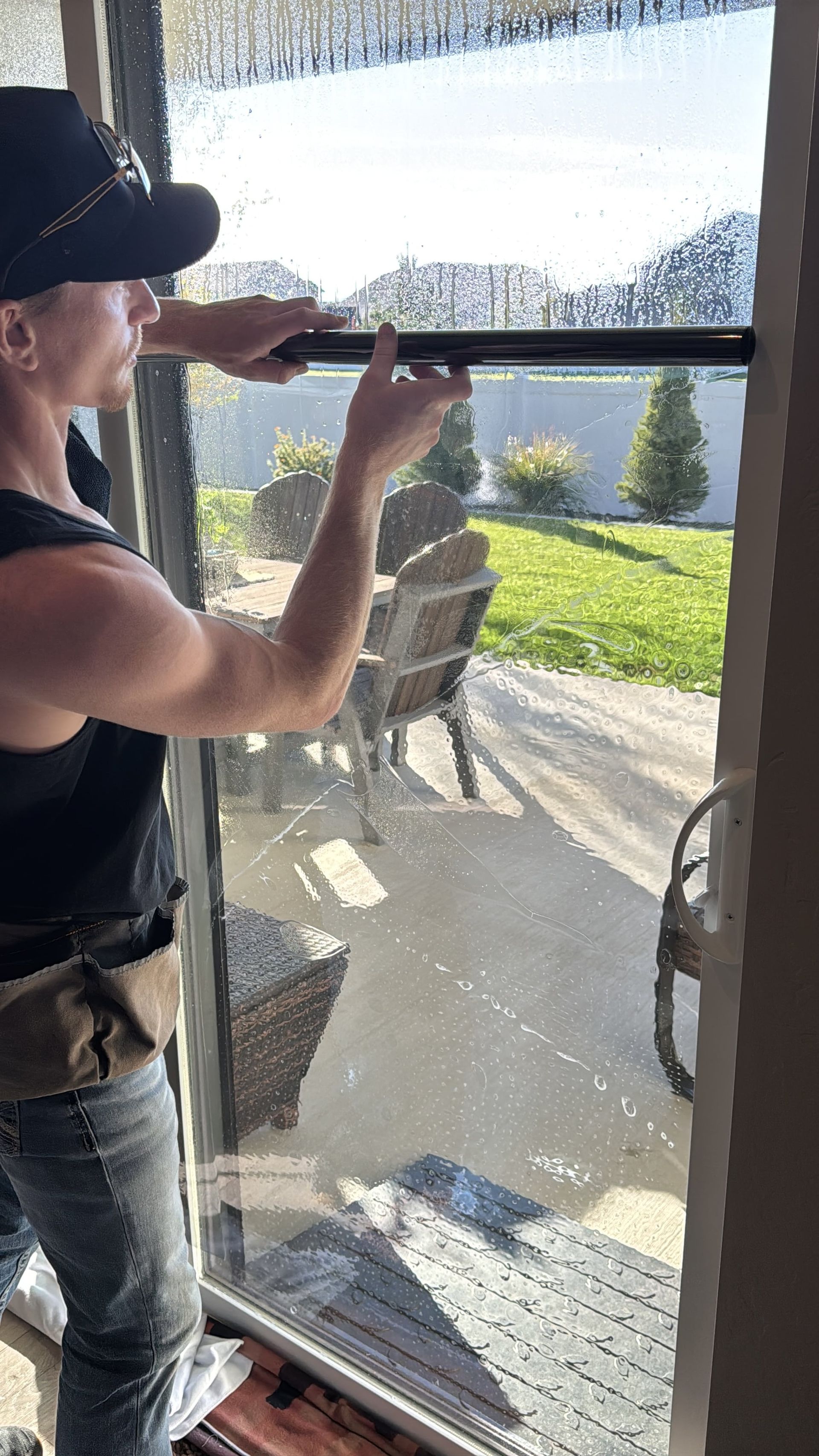 A man is installing window film on a sliding glass door.
