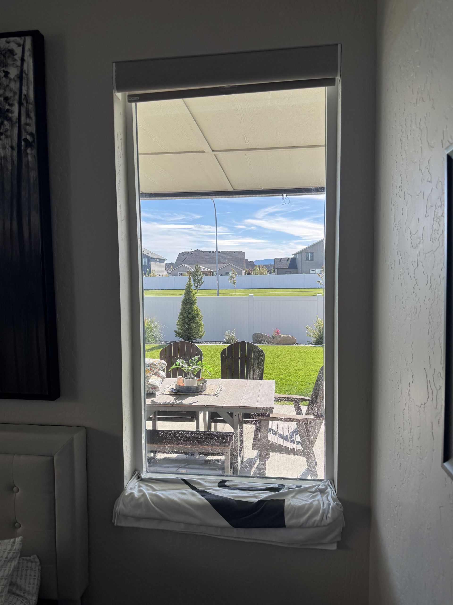 A window in a living room looking out to a patio with a table and chairs.