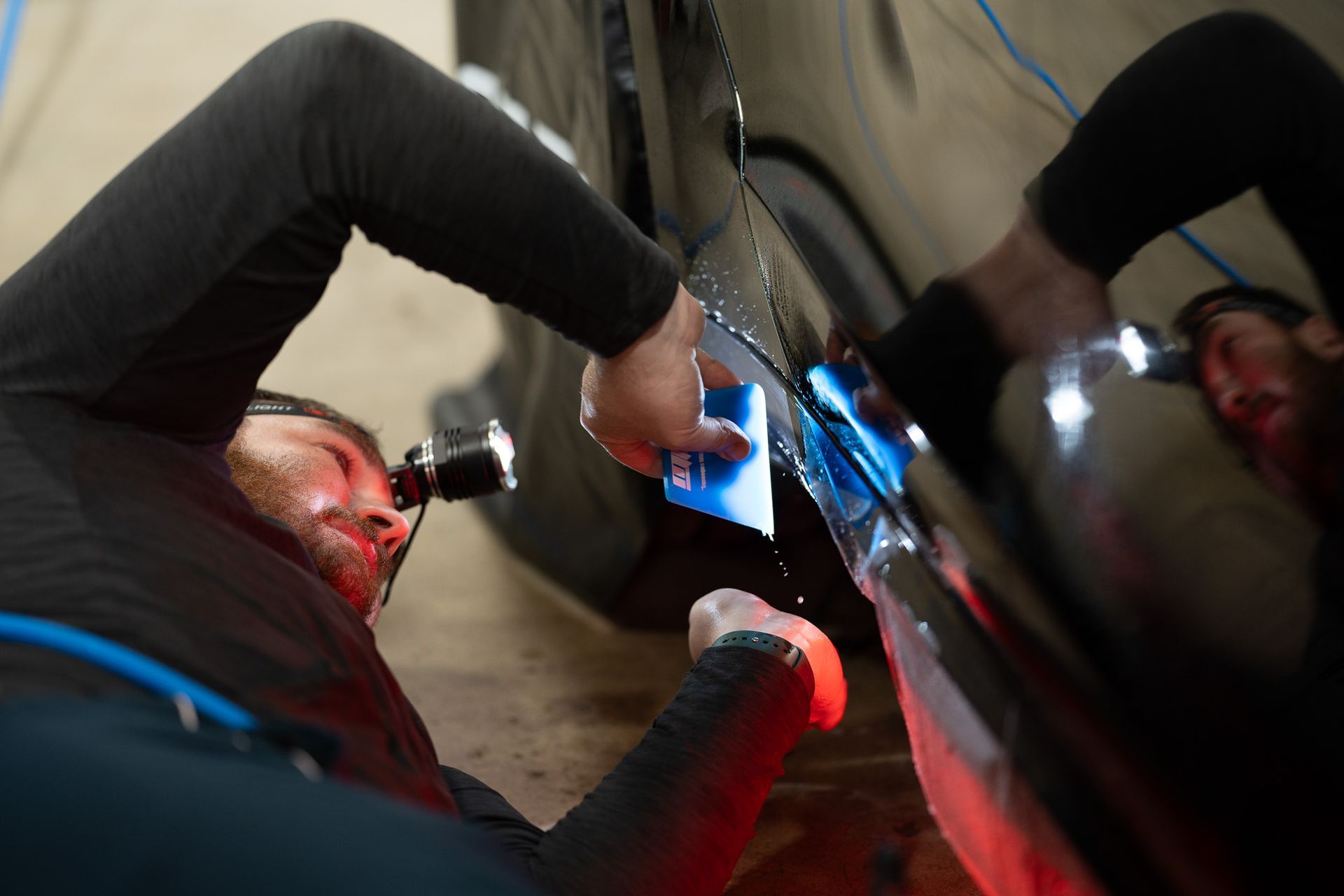A man is laying on the ground working on a car.