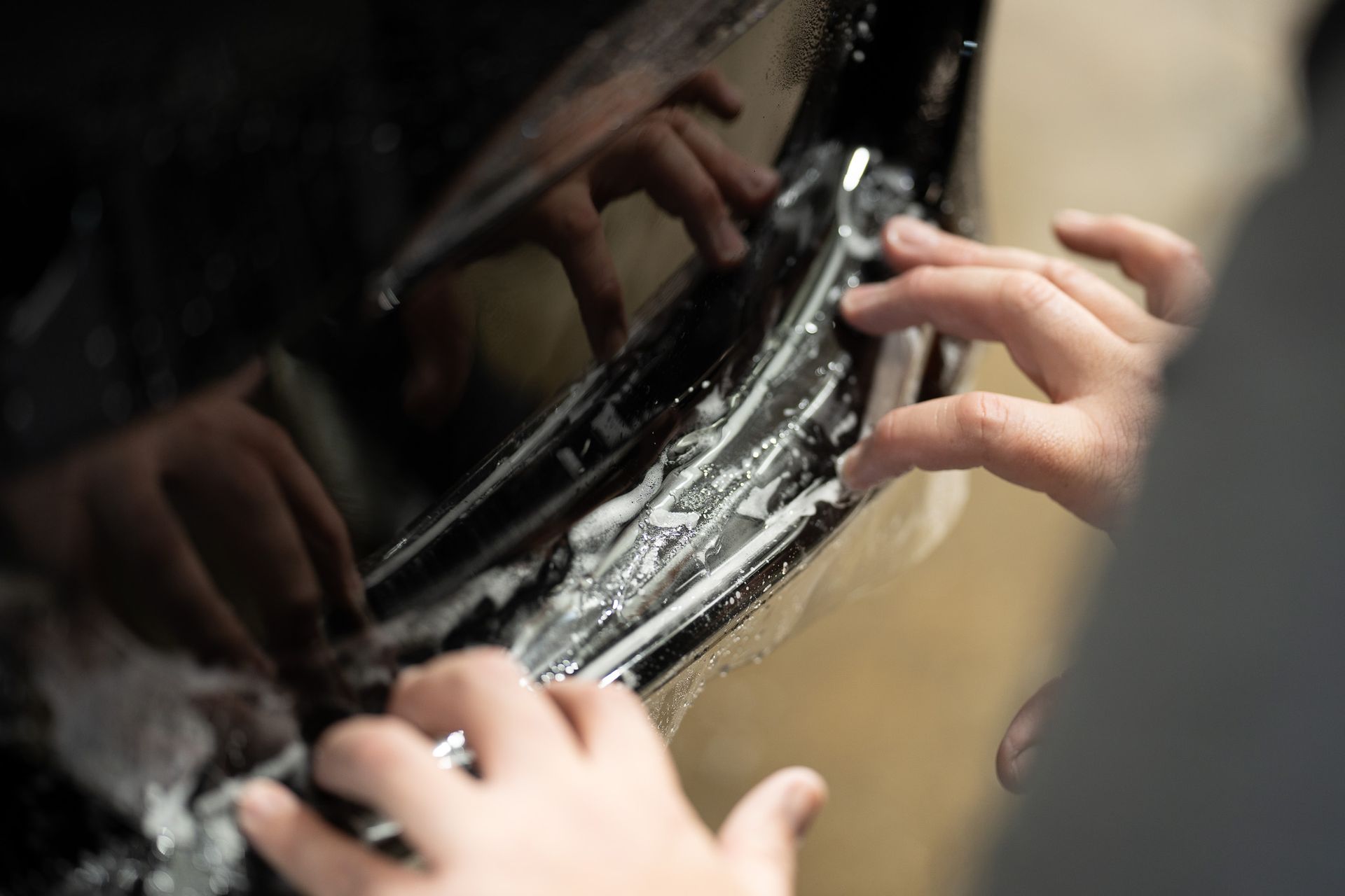 A person is applying a protective film to the side of a car.
