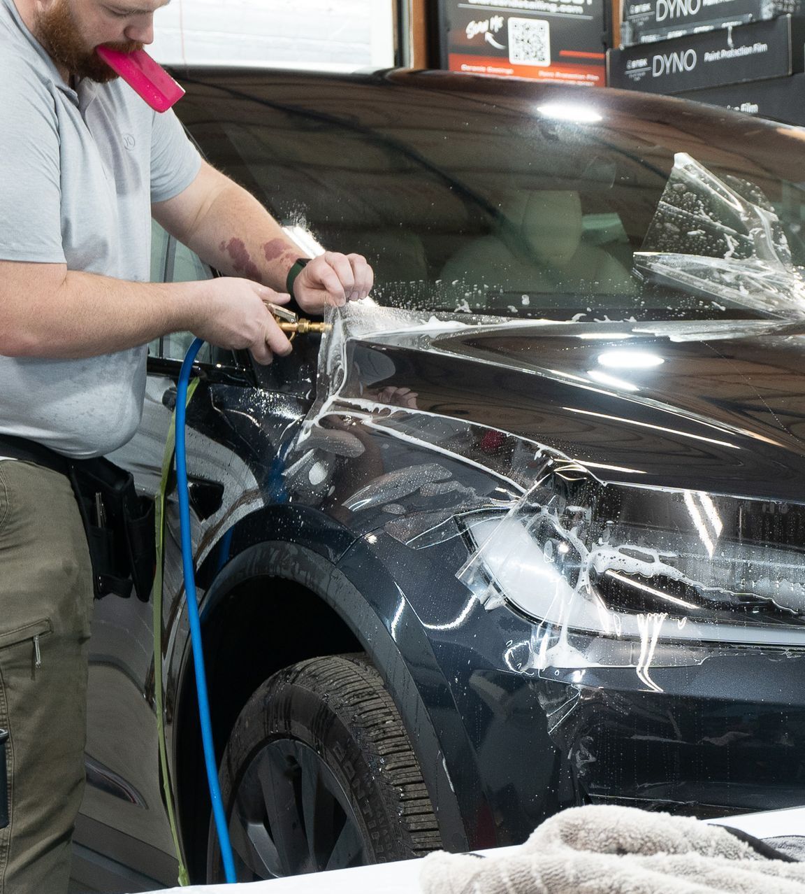 A man is polishing a black car with a hose