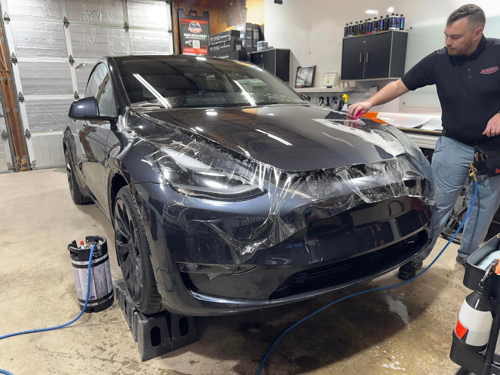 A man is wrapping a tesla model y in plastic.