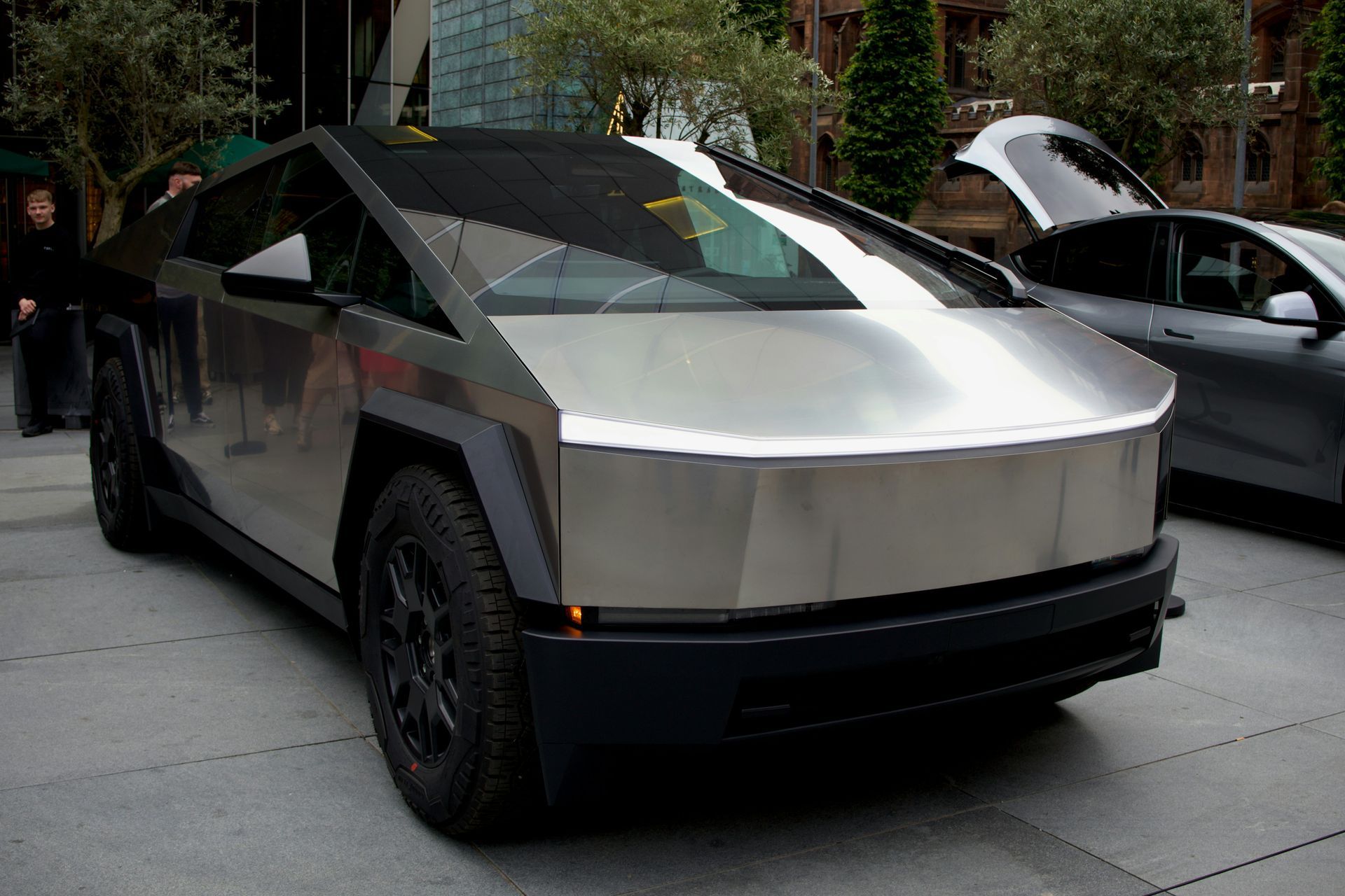 A silver tesla cybertruck is parked on the side of the road.