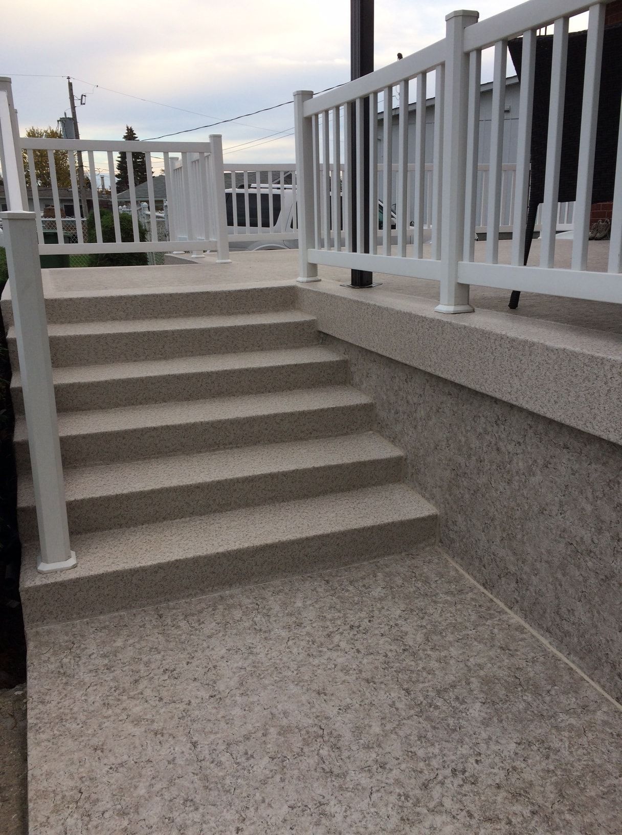 Un escalier menant à une terrasse en membrane de pvc avec une balustrade blanche