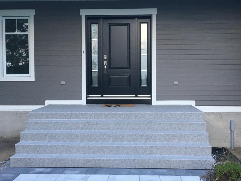 Une maison grise avec une porte et des marches recouvertes de membrane de pvc grise