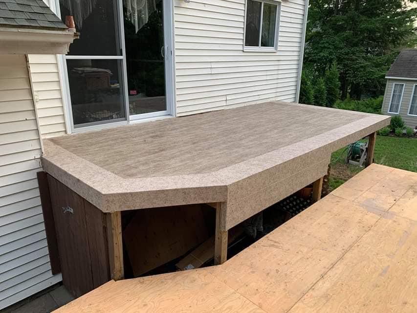 Une terrasse en membrane de pvc est en cours de construction sur le côté d'une maison.