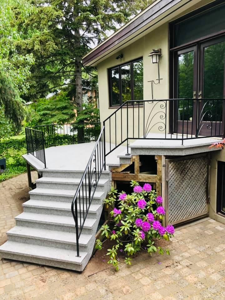 Une maison avec des escaliers qui y mènent et des fleurs devant.