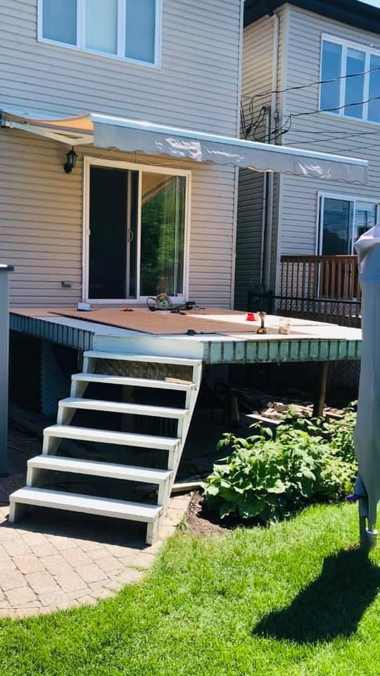 Une terrasse en membrane de pvc avec des escaliers qui y mènent devant une maison.