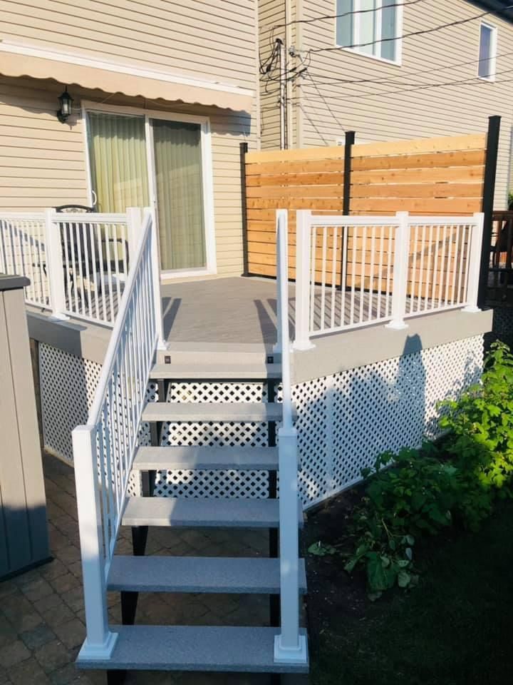 Une terrasse avec des escaliers en pvc qui y mènent et une balustrade en pvc blanche.