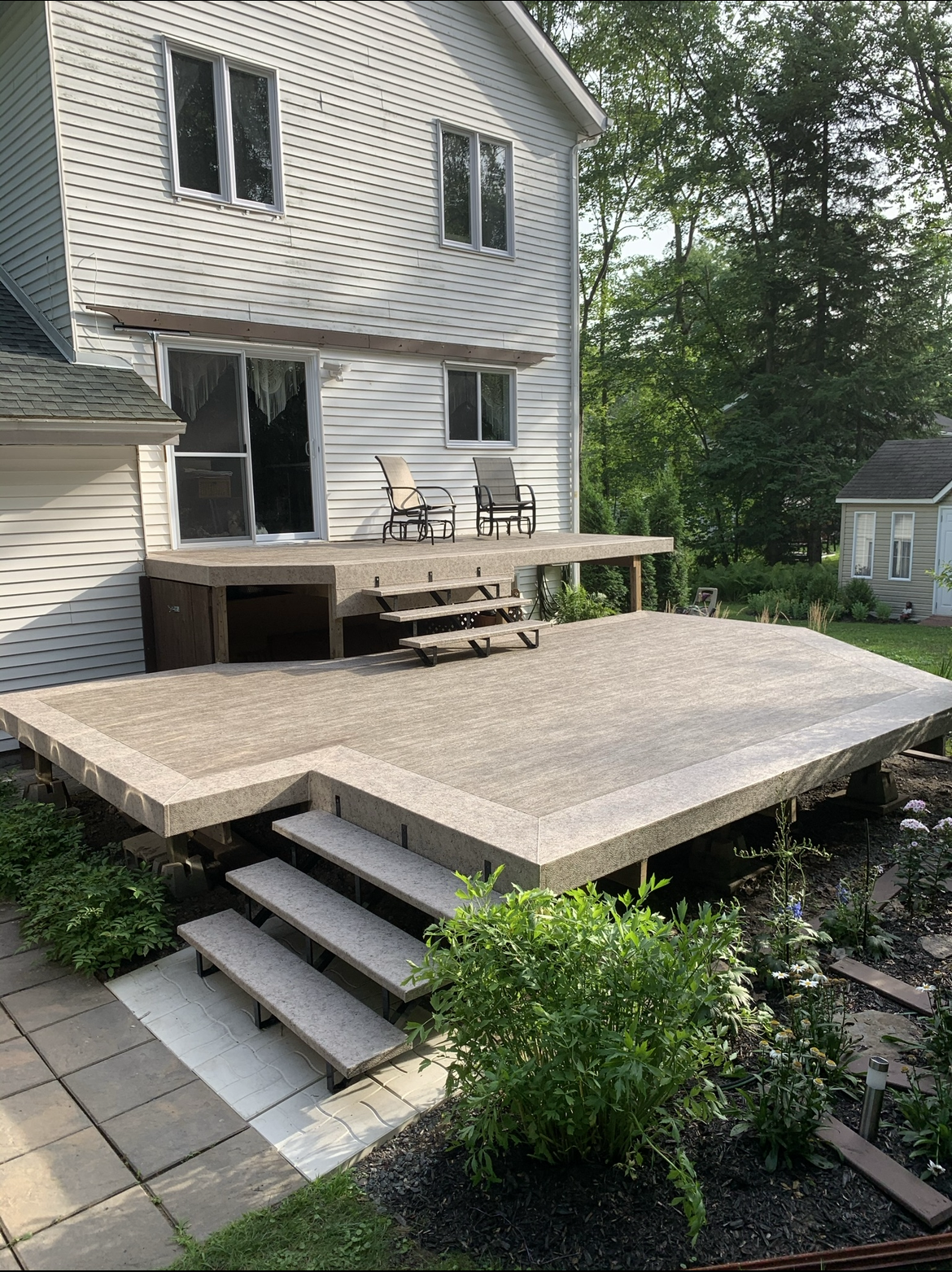 Une grande terrasse en membrane de pvc avec des escaliers se trouve devant une maison.