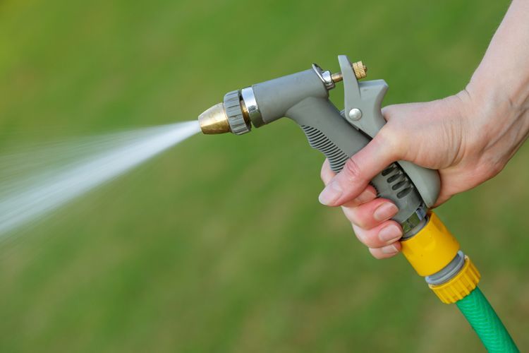 Gros plan sur une main qui tient un boyau d'arrosage