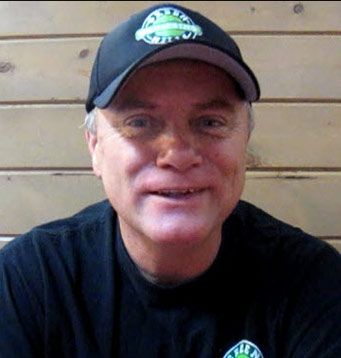 A man wearing a hat and a black shirt is smiling