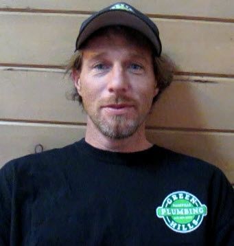A man wearing a black shirt that says green hills plumbing