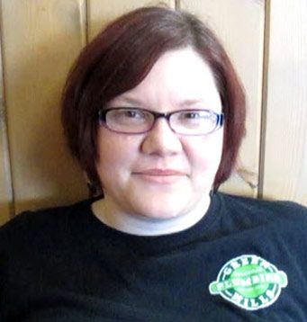 A woman wearing glasses and a black shirt that says plumbing