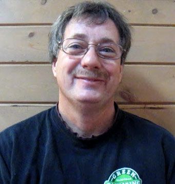 A man wearing glasses and a black shirt with the word green on it