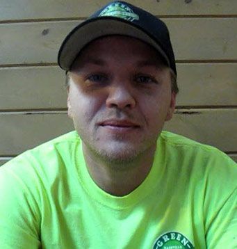 A man wearing a green shirt and a black hat