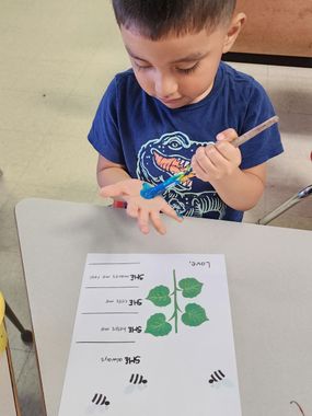 Childcare Franklin County — A Boy is Painting His Hand Blue In School in Columbus, OH