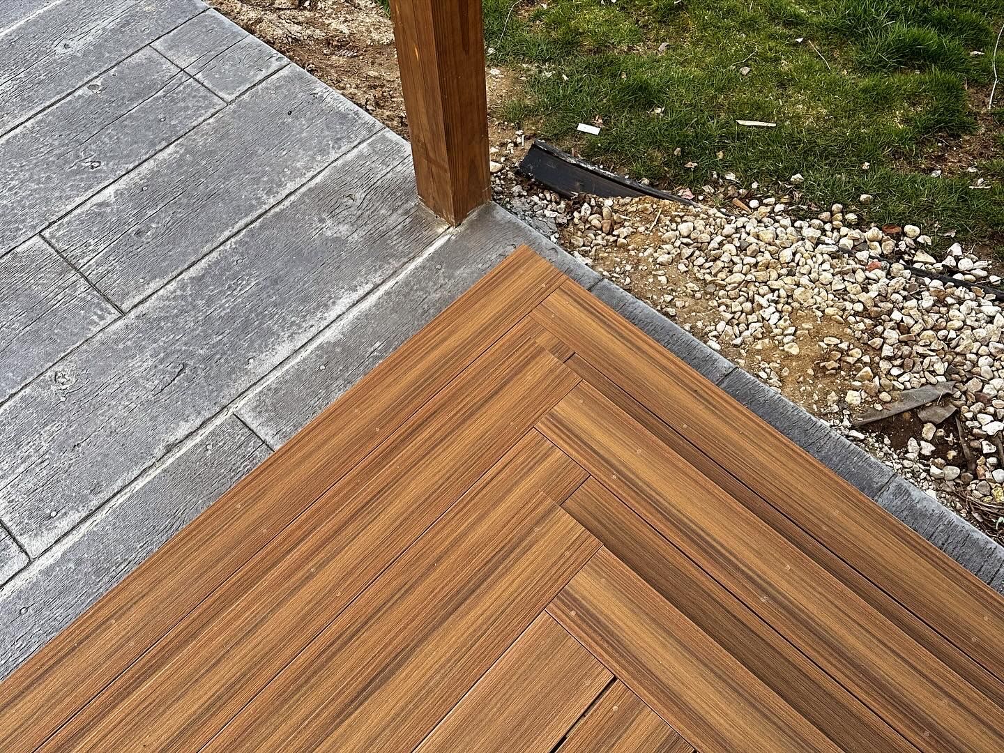 A wooden deck with a brick walkway in the background.