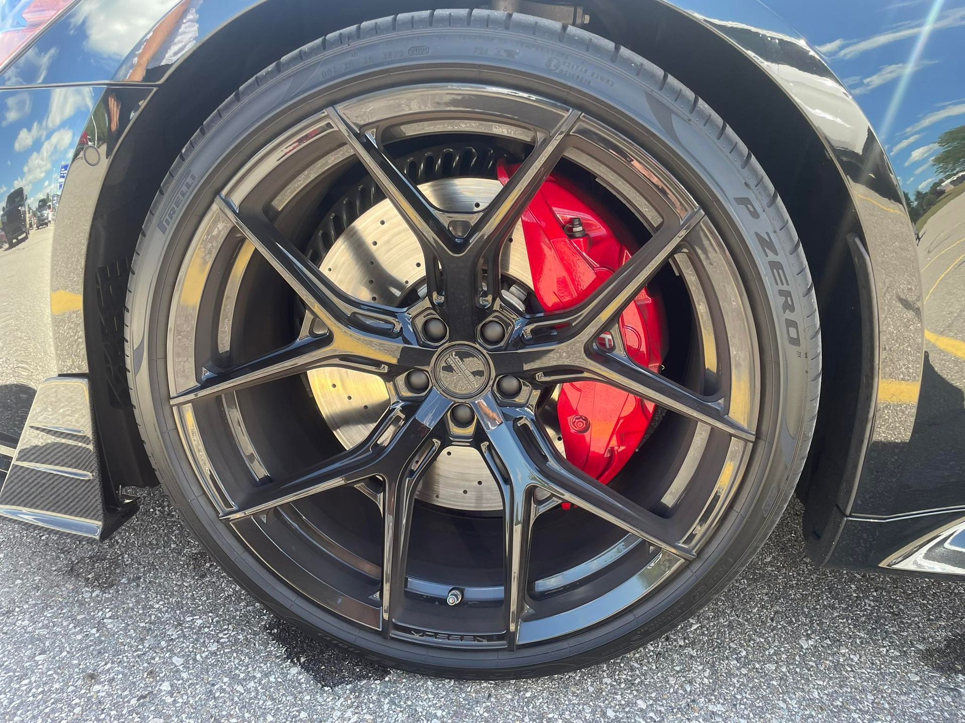 Black car wheel with glossy black rims, red brake calipers, and a Pirelli tire.