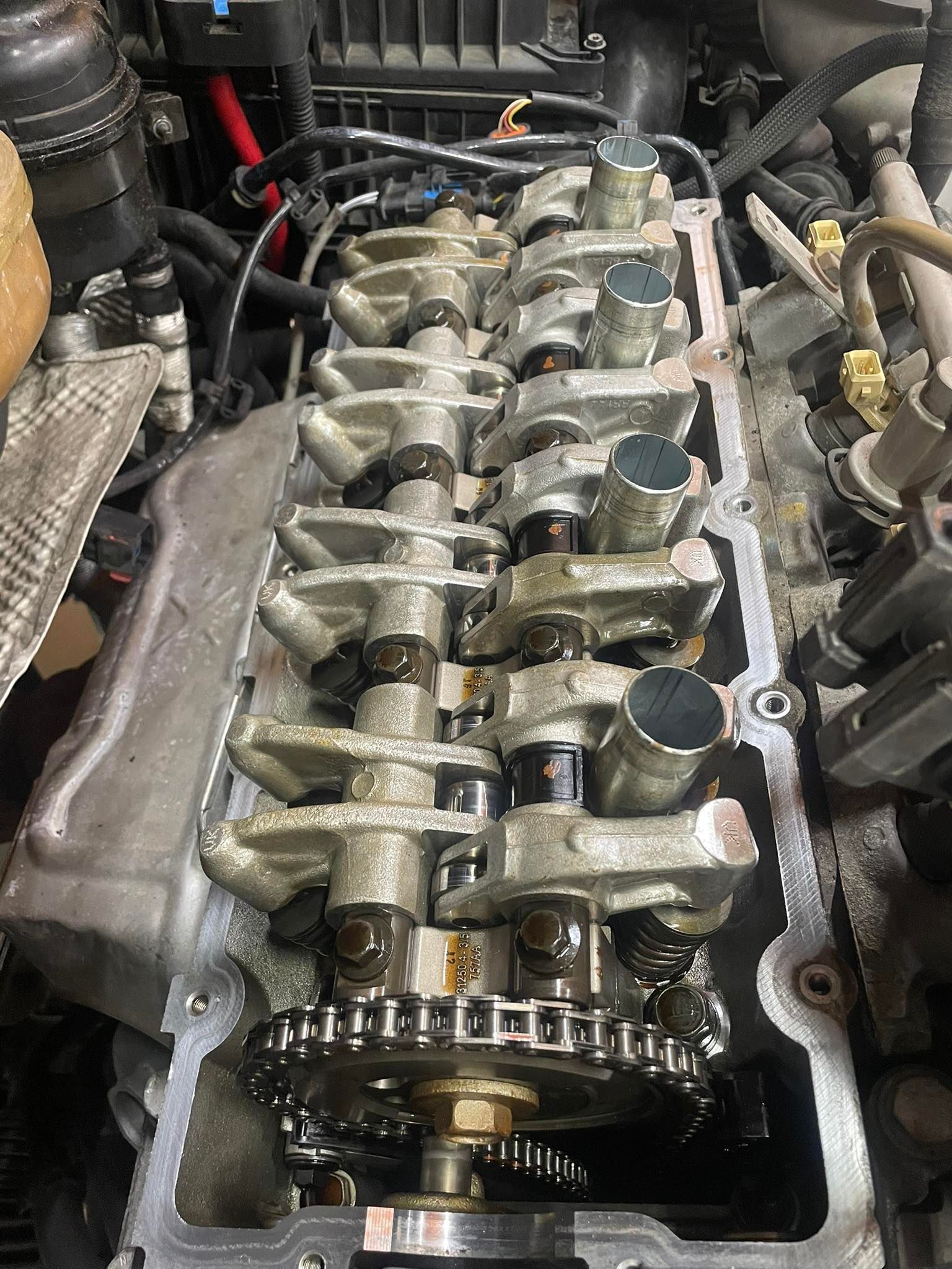 Engine cylinder head with camshaft, chain, and valves exposed.