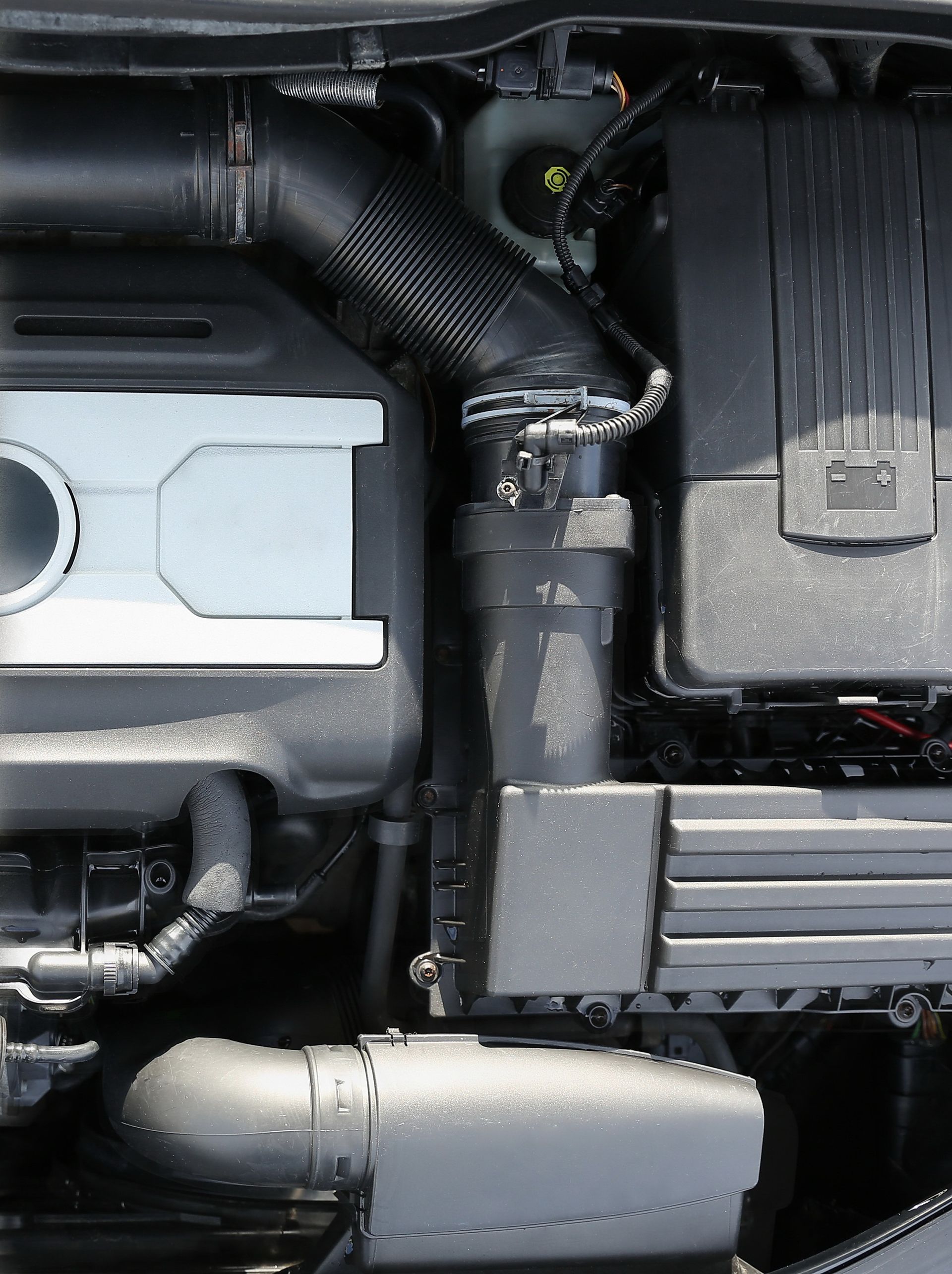 Engine compartment with black air intake tube and various components.