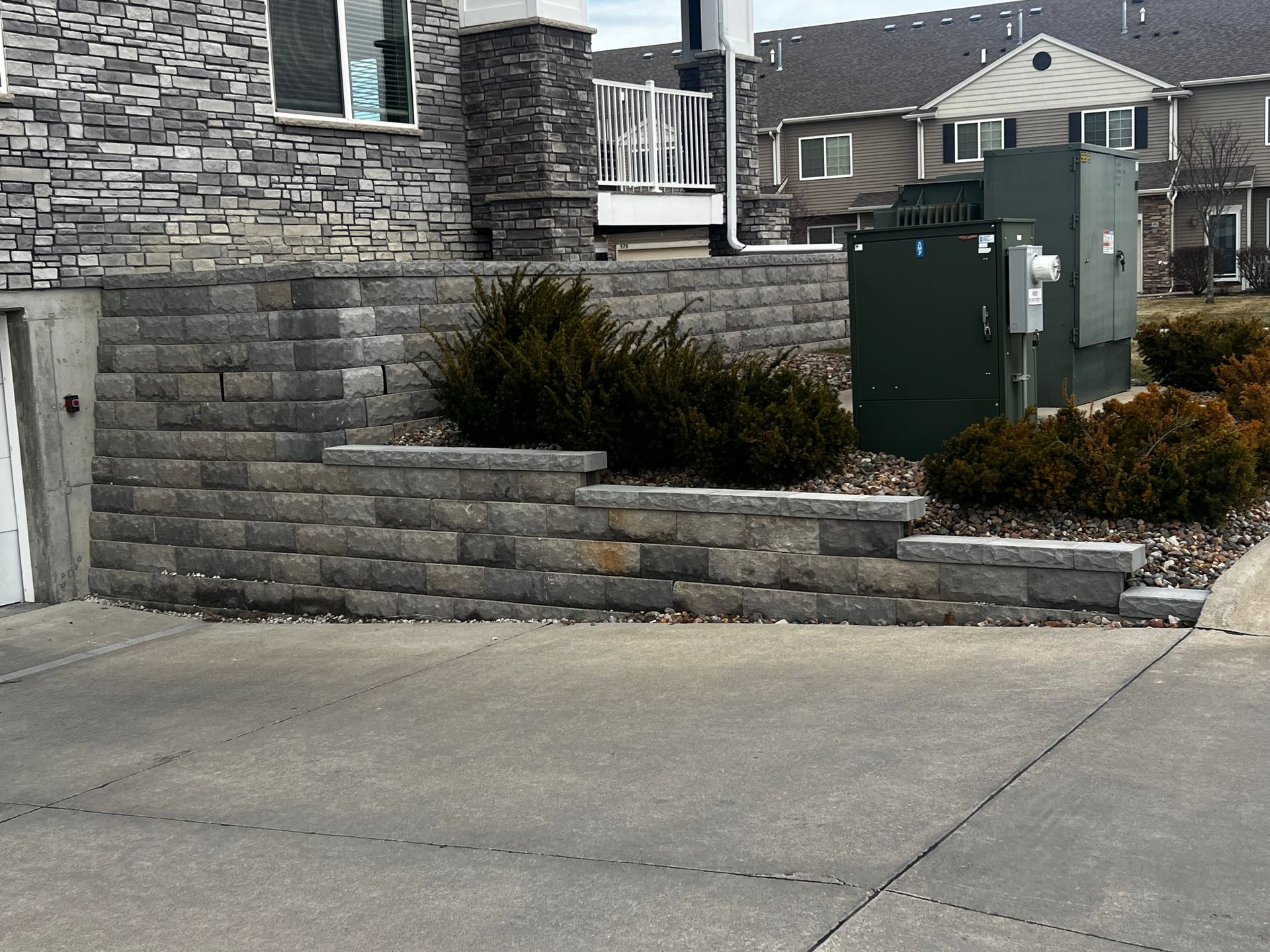 An archaeological site with exposed brick foundations and a large tree in a grassy area with steps.