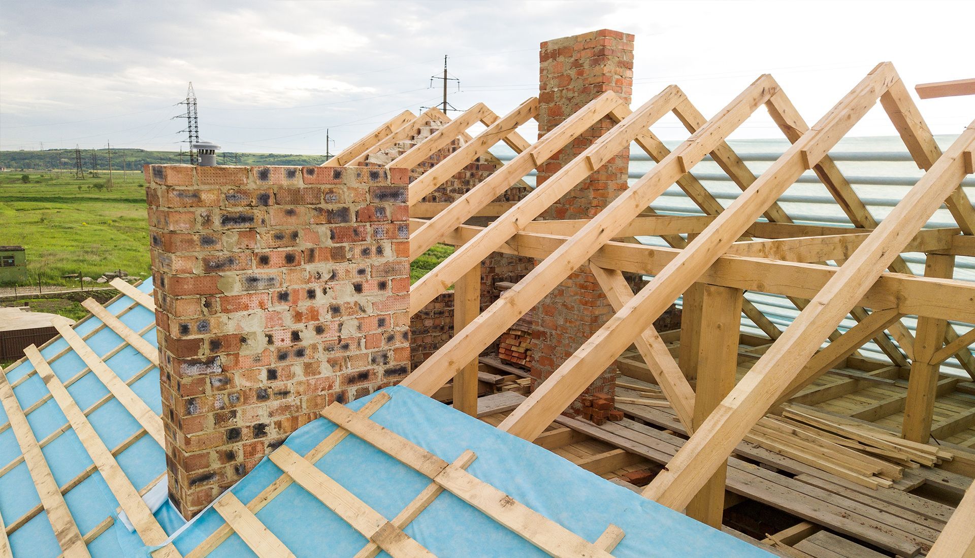 Construction worker in orange hoodie on lift, applying sealant to a concrete block opening.