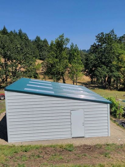 A red shed is sitting in the middle of a grassy field.
