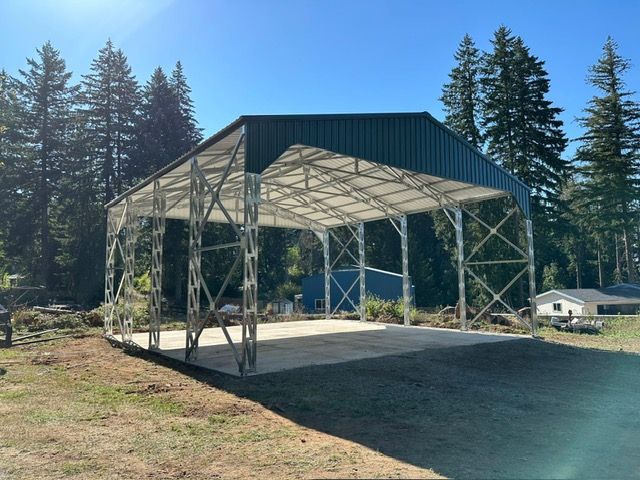 Green metal carport under a clear blue sky, surrounded by trees.
