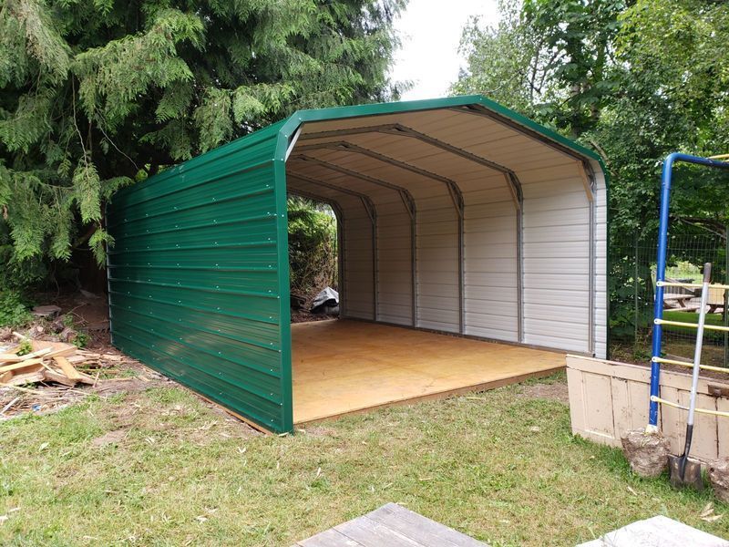 A green and white garage with a wooden floor in a backyard.