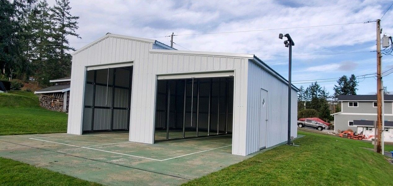 A white garage is sitting on top of a grassy hill.
