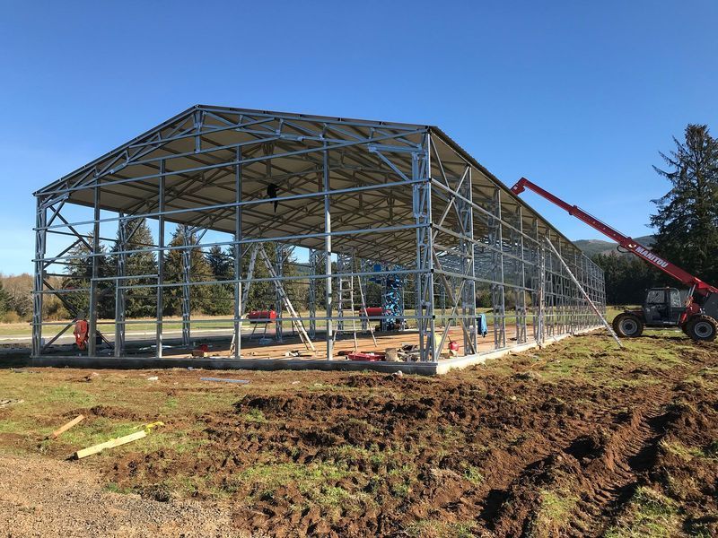 A large metal structure is being built in a dirt field.