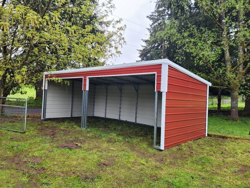 A large metal building is sitting on top of a gravel lot.
