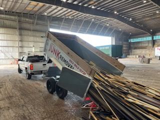 A truck dumping wood debris from a trailer inside a large warehouse.