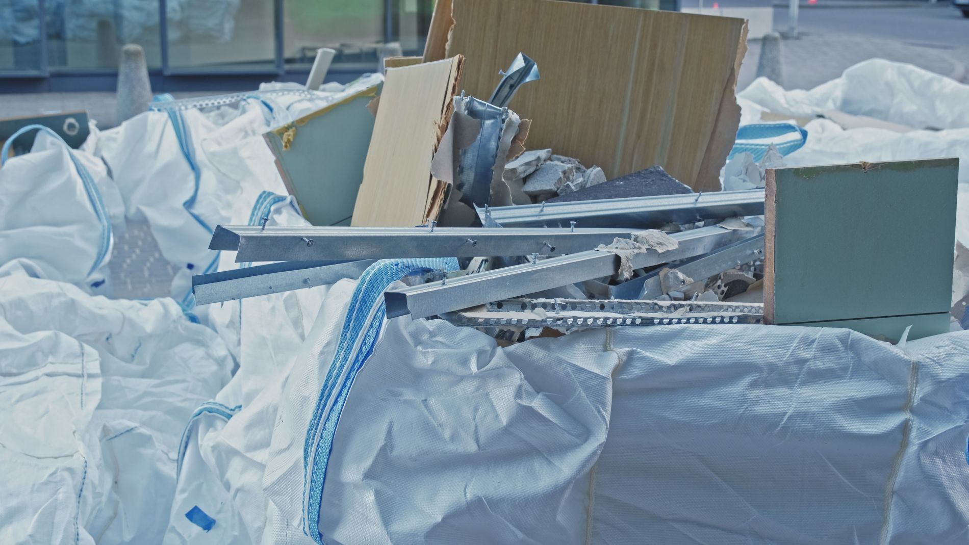 Pile of construction debris in white bulk bags, including cardboard and metal.