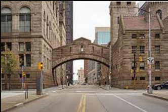 An empty city street with a bridge between two buildings.