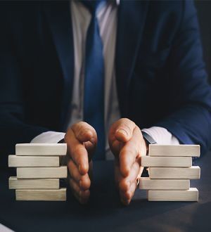 A man in a suit and tie is holding a stack of wooden blocks.