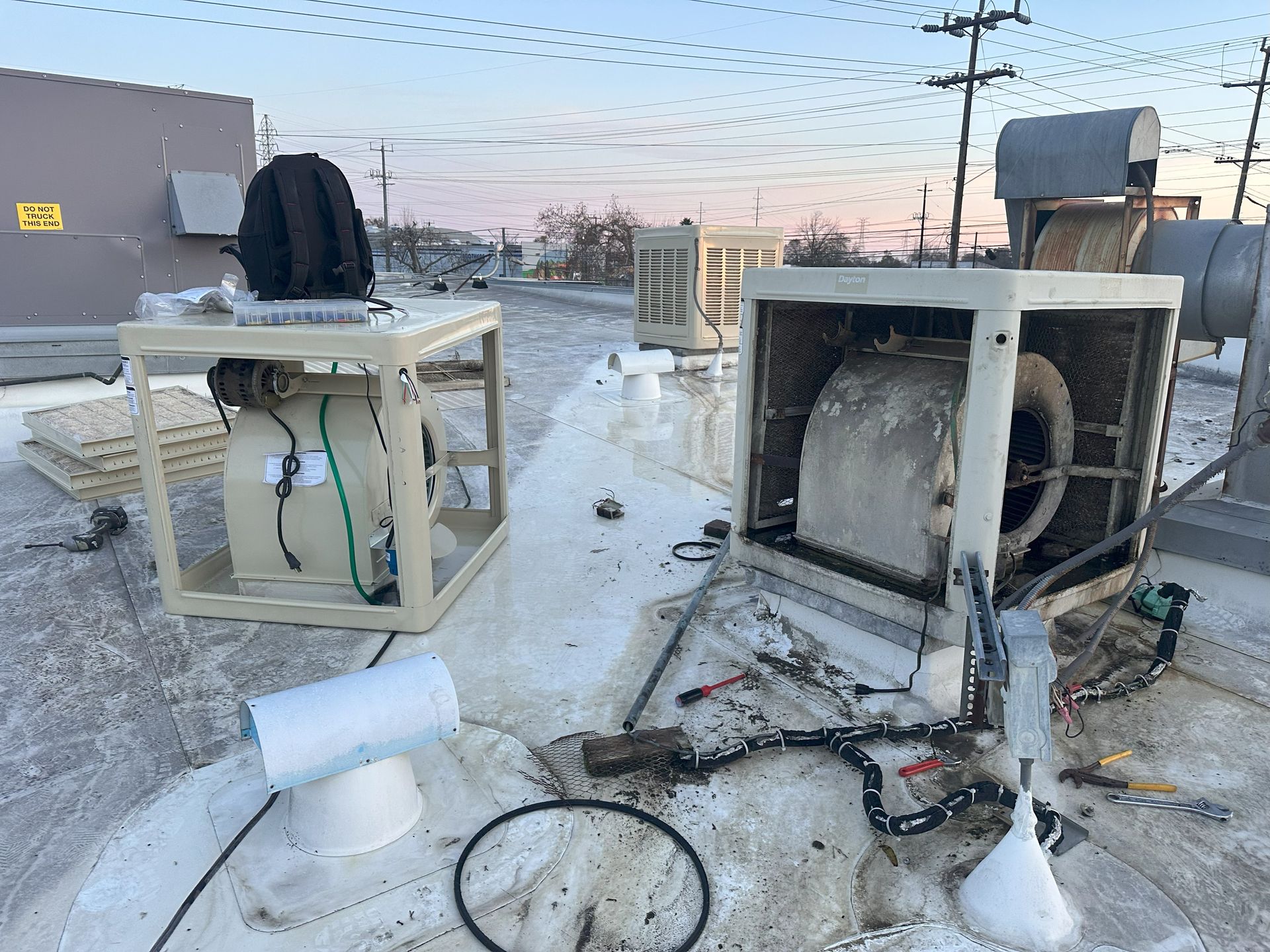 Two air conditioners are sitting on top of a snow covered roof.