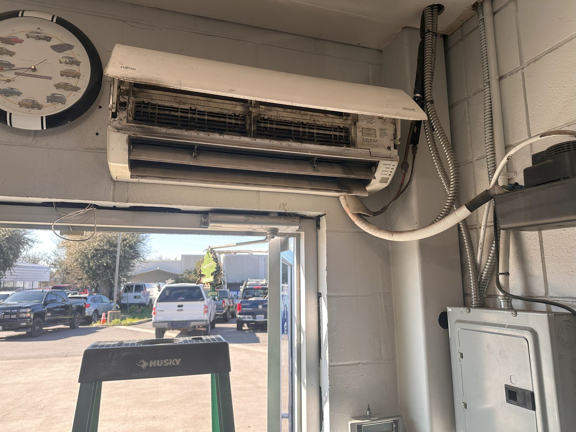 A clock hangs above an air conditioner in a building