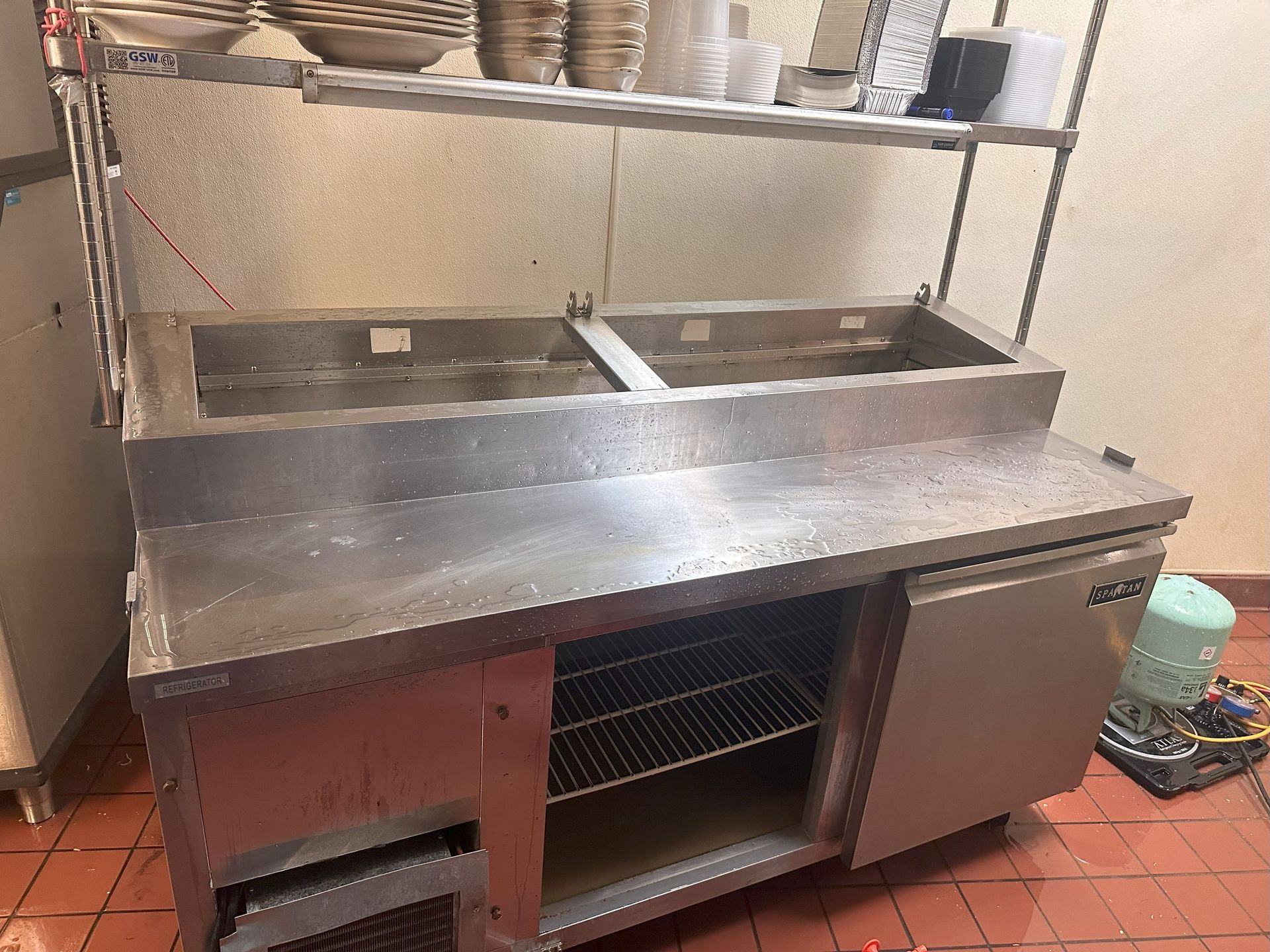 A stainless steel kitchen counter with two sinks and a refrigerator.