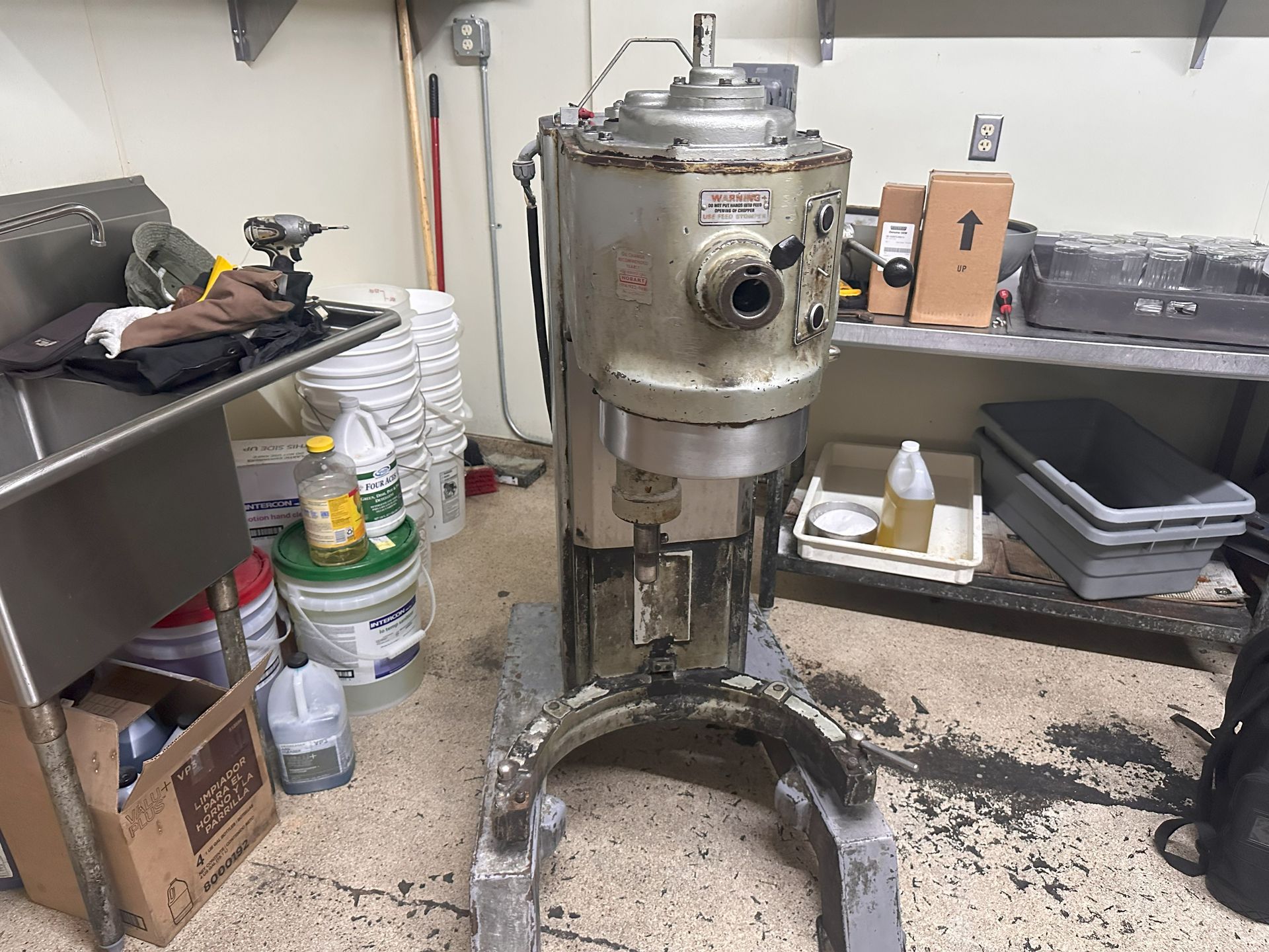 A large mixer is sitting in a messy kitchen next to a sink.