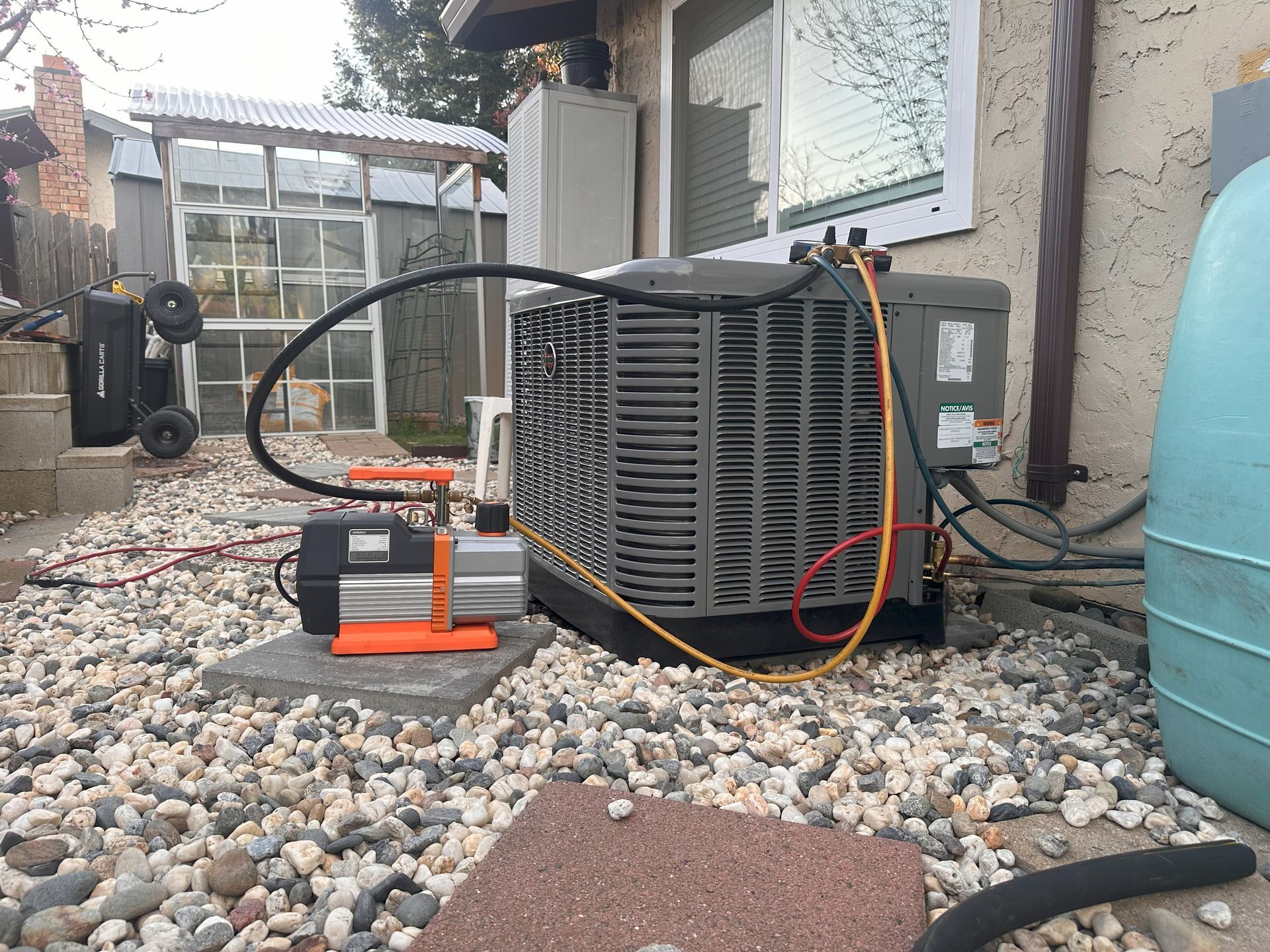 An air conditioner is being serviced outside of a house