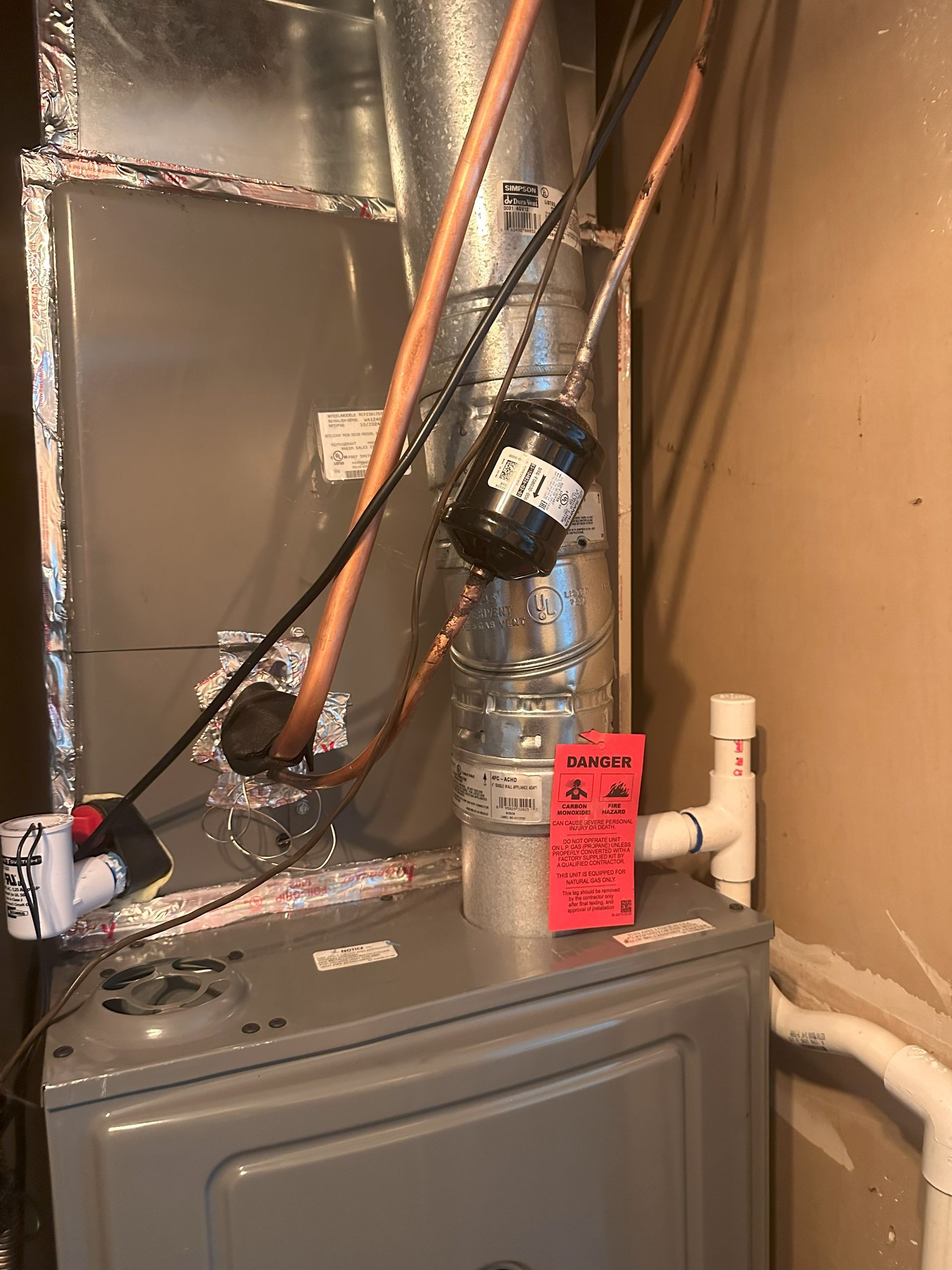 A heater with a red tag on it is sitting in a room next to a wall.