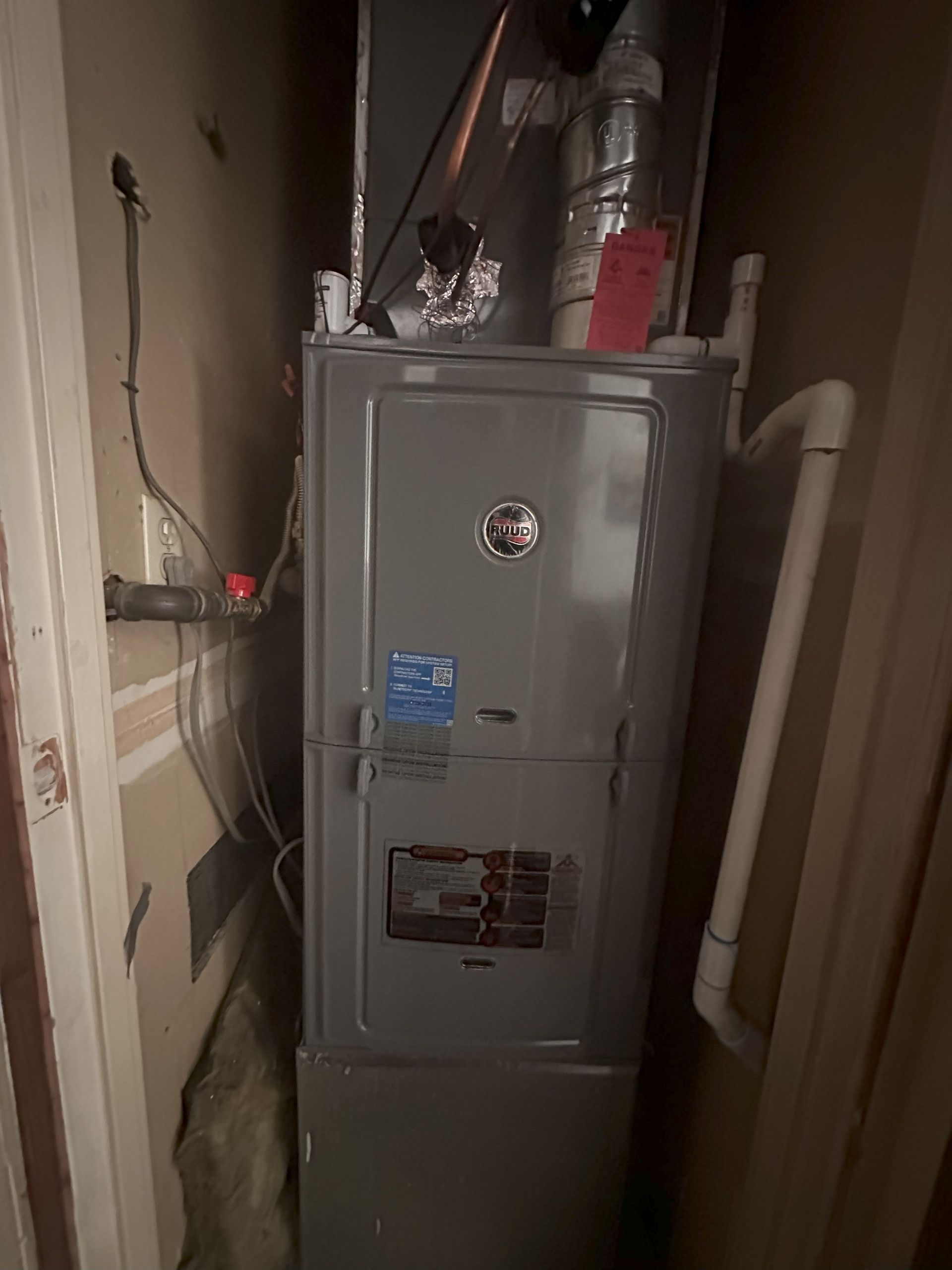 A furnace is sitting in a corner of a room next to a door.