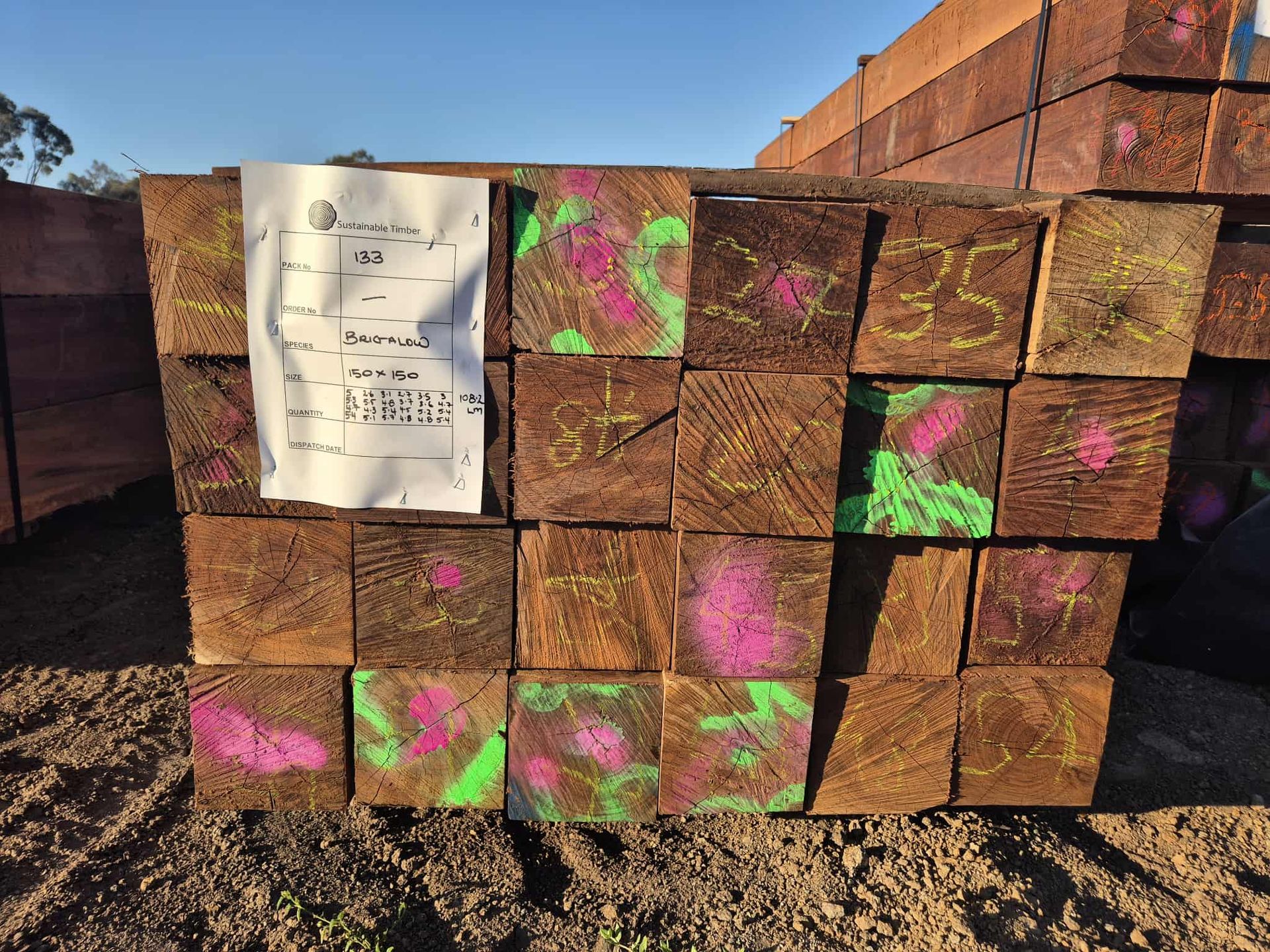 Stack of brown timber blocks with pink and green markings; paper on top.