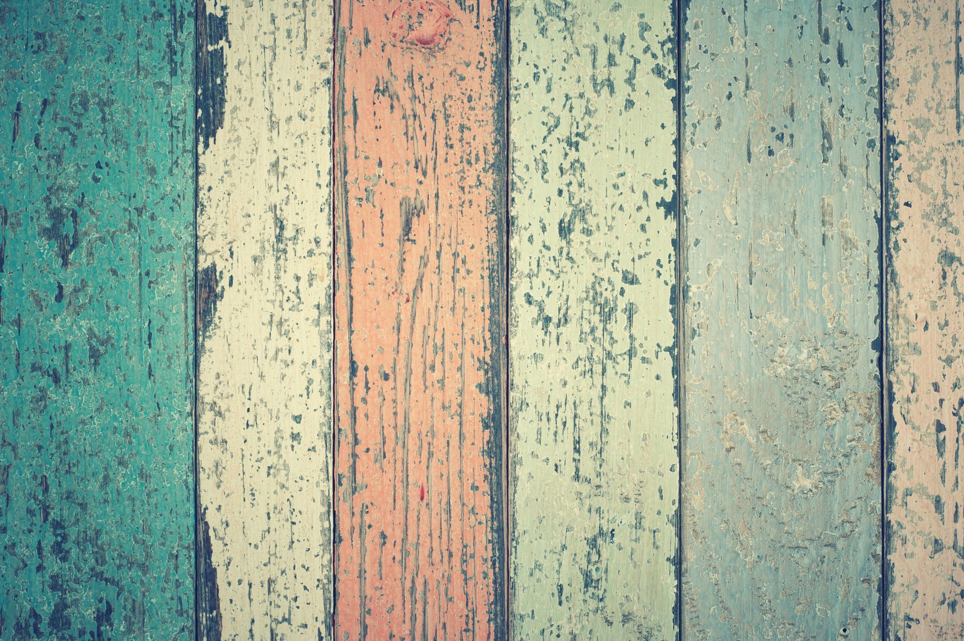 Vertical wooden planks painted in faded shades of teal, cream, peach, and blue.