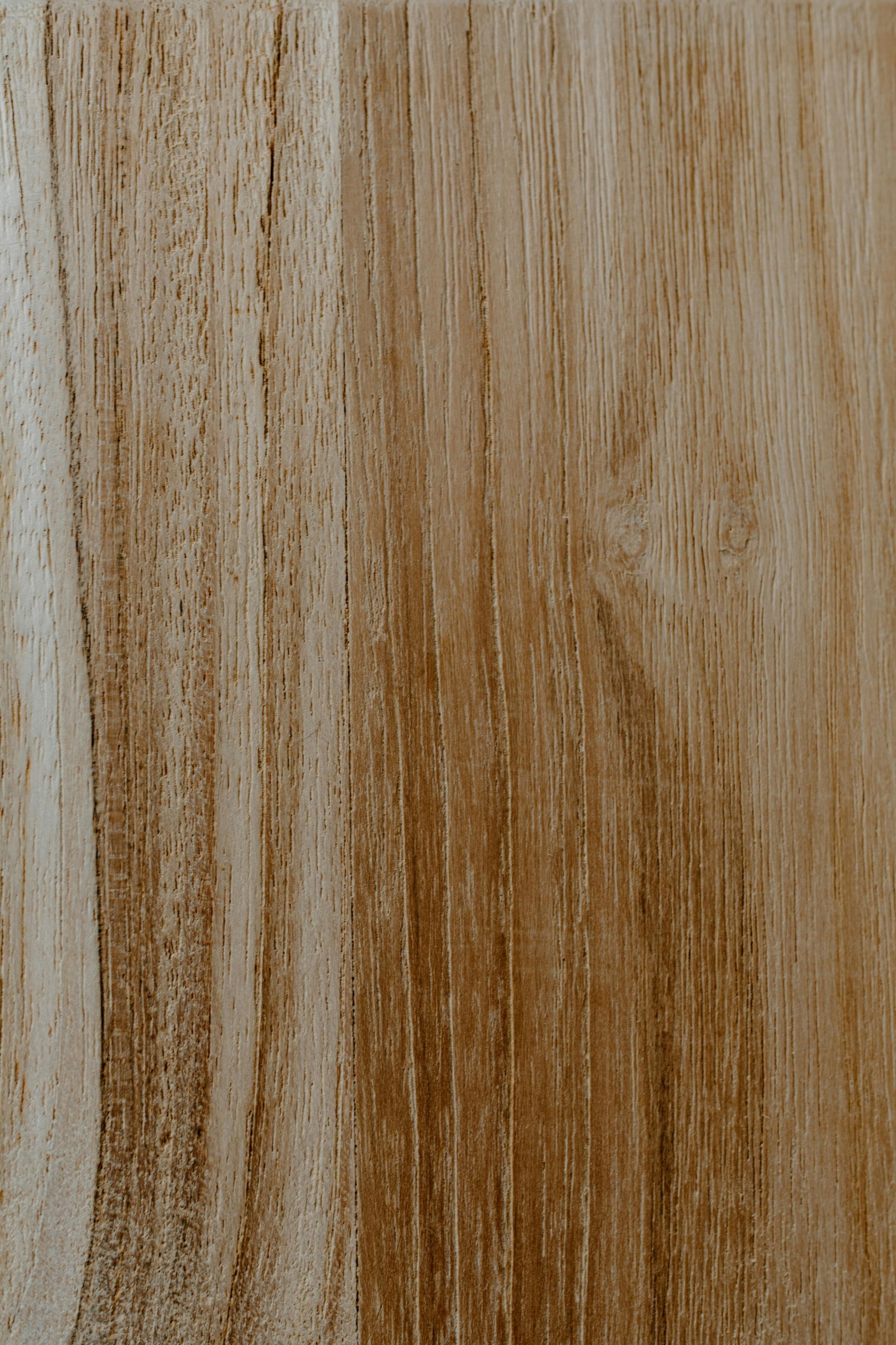 Close-up of light brown wood grain with vertical lines and variations in color.