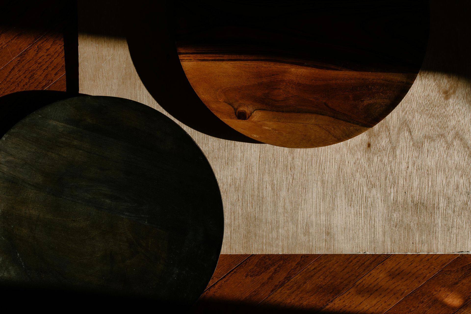 Two dark circles on a wood background with light and shadow, contrasting colors of brown and gray.